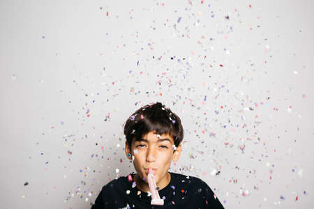 Portrait of a ten years old boy throwing confetti to the airの写真素材