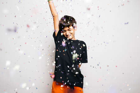 Portrait of a ten years old boy throwing confetti to the air