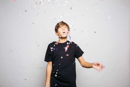 Portrait of a twelve years old boy throwing confetti to the airの写真素材