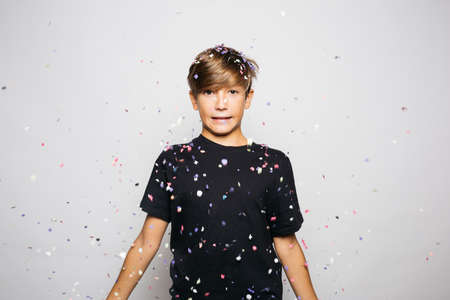 Portrait of a twelve years old boy throwing confetti to the air