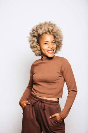 Portrait of Smiling Young woman wearing brown clothes while standing Against White Background