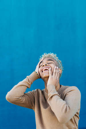 Portrait of an smiling young latin american male against a blue backgroundの写真素材