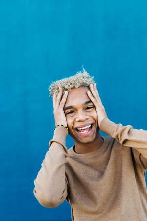Portrait of an smiling young latin american male against a blue backgroundの写真素材