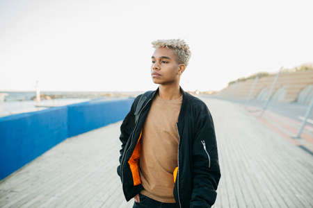 Portrait of a young latin american male standing during sunset on a urban scapeの写真素材