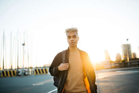 Portrait of a young latin american male standing during sunset on a urban scapeの写真素材
