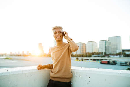Portrait of a young latin american male standing during sunset on a urban scapeの写真素材