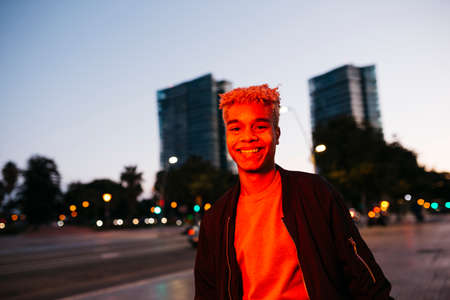 Young latin american student male under a red light walking on the street at duskの写真素材