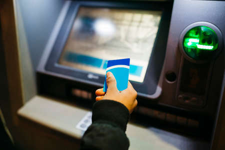 Hand of a Young latin american male with a blue credit card on a bank cashier, at duskの写真素材