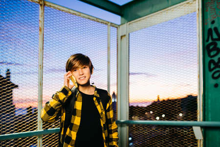Teenager using a red smartphone and sitting on stairs outdoors