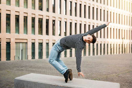 Young man doing acrobatic dance on a street benchの写真素材