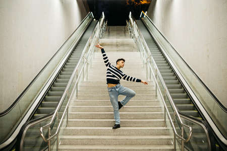 Young man dancing on the subway station stairs
