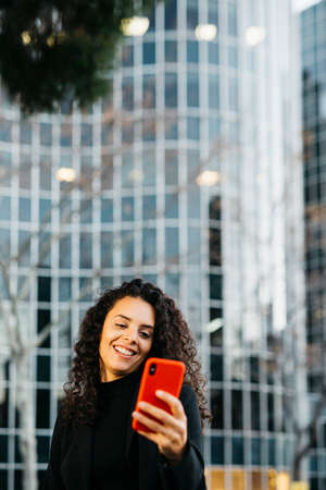 Young business woman talking on a red smartphone on the streetの写真素材