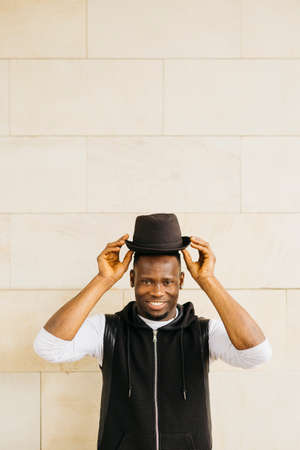 Portrait of a young black male taking off his black hat