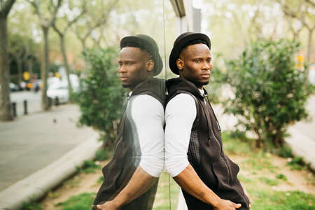 Portrait of a young black male standing against a window shopの写真素材