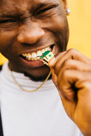 Young black male biting a Senegal shaped medal with its flag on it held by a black maleの写真素材