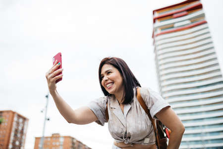 Young brunette woman taking a selfie on the street