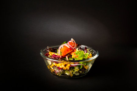 Green salad in a big bowl over a black backgroundの写真素材