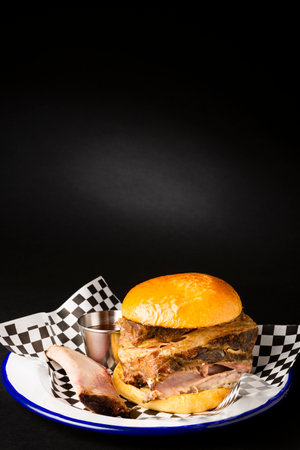 Beef rib burger and it's bone on a white plate over a black backgroundの写真素材