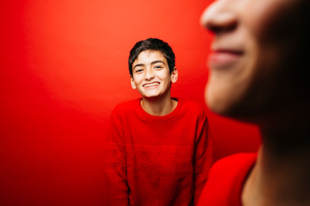 Two Pre-adolescent boys wearing a red sweater over a red backgroundの写真素材