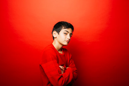 Pre-adolescent boy wearing red over a red background with a cool attitudeの写真素材