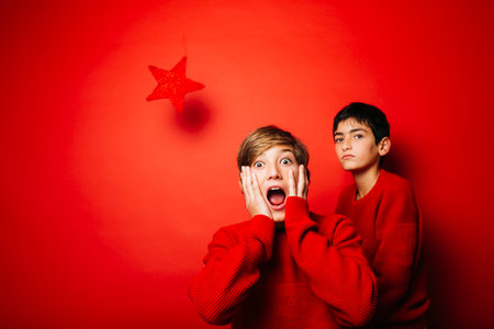 Two Pre-adolescent boys, wearing a red sweater, playing over a red backgroundの写真素材