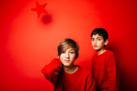 Two Pre-adolescent boys, wearing a red sweater, playing over a red backgroundの写真素材