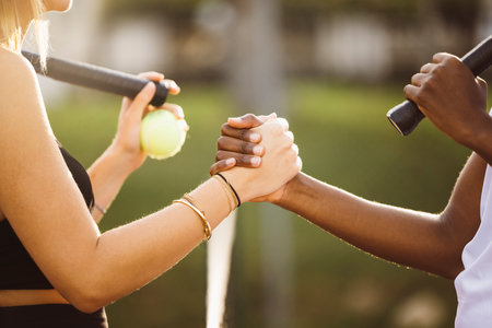 Amateur tennis players shaking hands at the net. Two sportswomen shaking hands over the net after the match.の写真素材