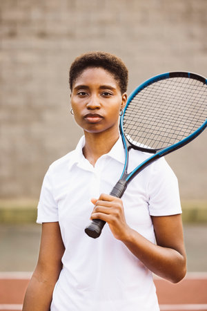 Portrait of a young beautiful women with tennis clothes and racket in a tennis court ready to play a game.の写真素材
