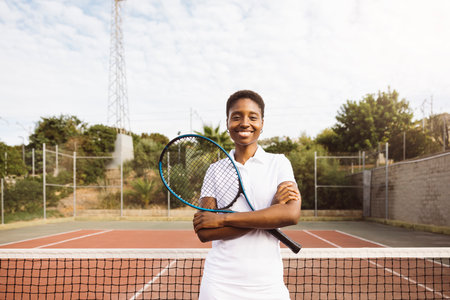Portrait of a young beautiful women with tennis clothes and racket in a tennis court ready to play a game.の写真素材