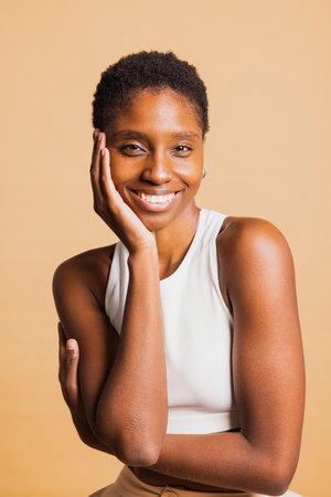 Portrait of a young beautiful african american woman standing against brown background looking at camera with her arms crossed. Young woman standing with her arms crossed.の写真素材