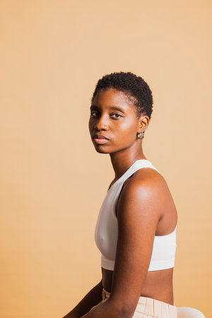 Portrait of a serious young beautiful african american woman standing against brown background...