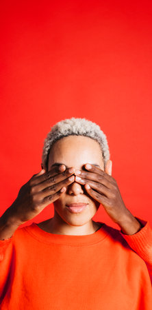 Portrait of young woman with her eyes covered by another woman's hands.の写真素材