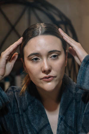 girl tidying up her hair wearing a bathrobeの写真素材