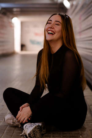 Girl sitting on the ground of a subway tunnel while laughingの写真素材