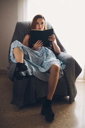 Girl reading a book in a couch in sexy poseの写真素材