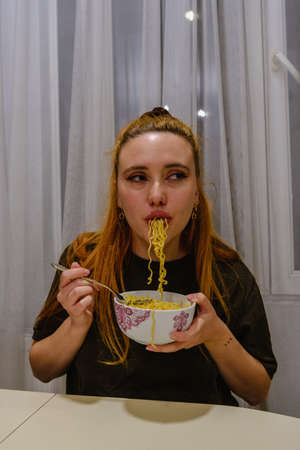 Girl eating asian noodles whit a forkの写真素材