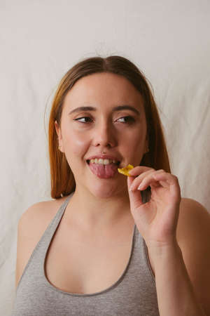 red-haired girl in sports bra sticking out her tongue while having a healthy snackの写真素材