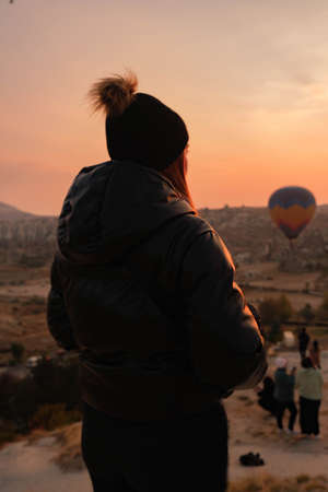 Girl from behind with hat and jacket contemplating the sunrise.の写真素材
