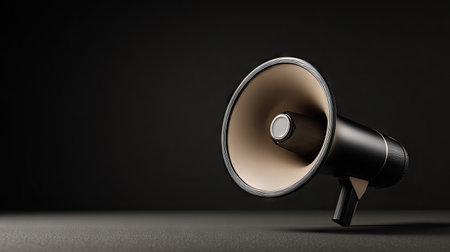 A dark illustration features a black megaphone against a shadowy backdrop. The image utilizes a minimalist design with a focus on shape and form. The lighting creates contrast and emphasizes the object's texture. Suitable for various projects requiring visual communication or announcements.の素材
