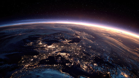 An aerial view presents planet Earth emerging from a dark expanse with a luminous atmospheric edge. Illuminated city lights punctuate the night, contrasted by the rising sun's golden glow. This image's composition and lighting make it suitable for various commercial applications in science, education, or conceptual designs.の素材