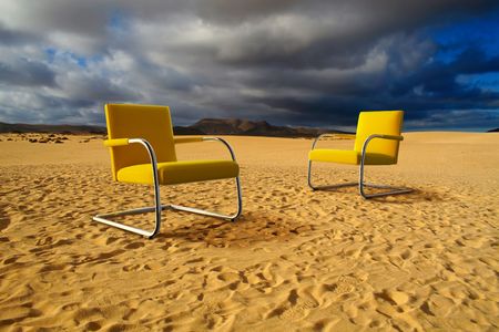 Two modern yellow chair in sand desertの写真素材