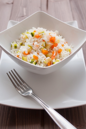 Basmati rice with carrots and courgettes in a dish on wood tableの写真素材