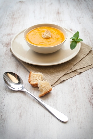 Bowl of pumpkin soup with bread crouton on white wood tableの写真素材