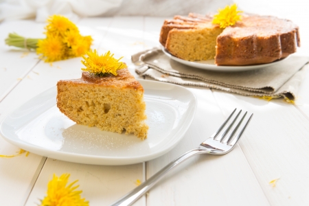 Cake with dandelion's flowers on a white wood table