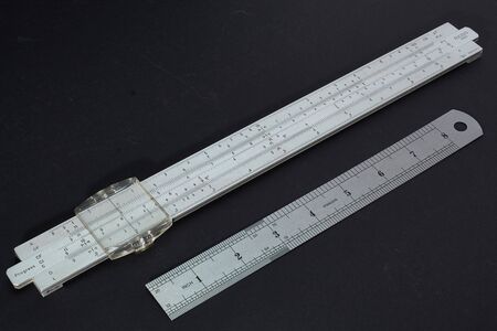 old slide rule made of metal from 1965 with a ruler for size comparisonの写真素材