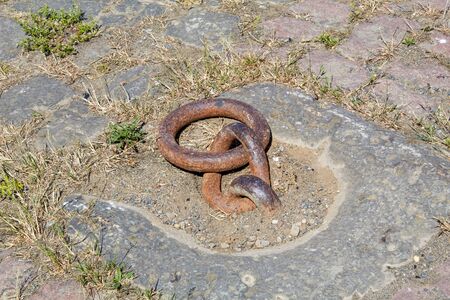In the ground anchored old rusted iron ring for mooring the Elbe steamer in Germanyの写真素材