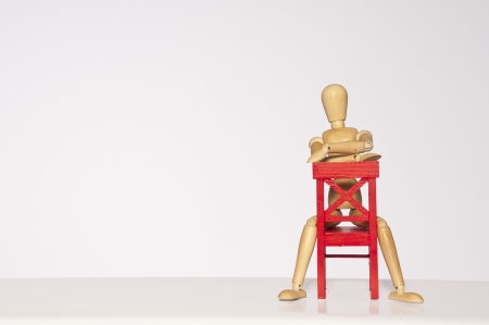 Wooden mannequin sitting on a red chairの写真素材