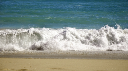 a wave on a sandy beach comes to shore.の写真素材