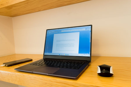 Laptop on a wooden table with a pen and mouse in the background