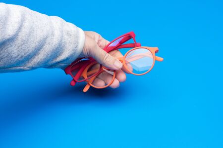 Eyeglasses in the hand of an adult; Colored glasses and lenses, modern, with corrected crystals to give a correct vision and to see from far and near.の写真素材